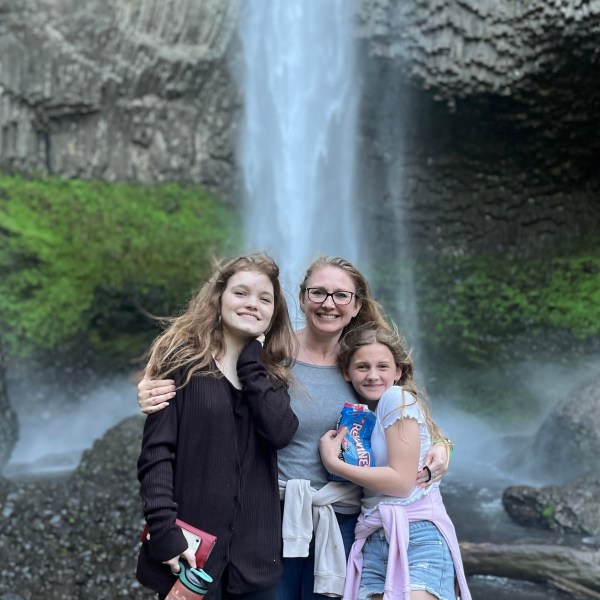 a little girl standing next to a waterfall