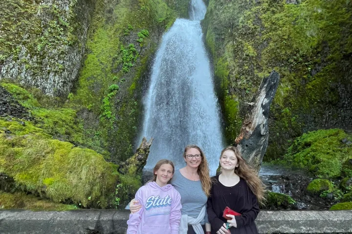 a woman standing next to a waterfall