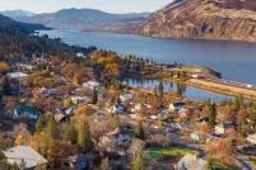 Aerial view of a lakeside town surrounded by trees and hills during autumn.