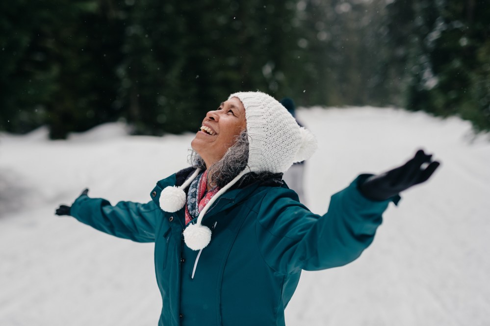 Person in winter clothing joyfully looking up in snowy mt hood forest.